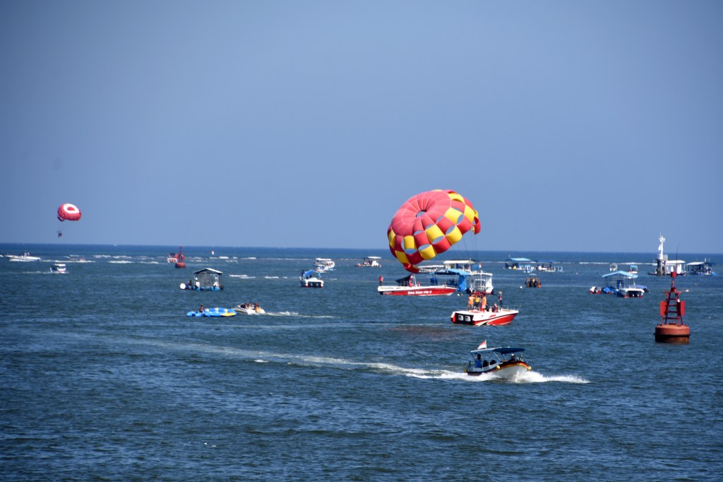 Pleasure craft and para-gliding outside Benoa Poet, Bali
